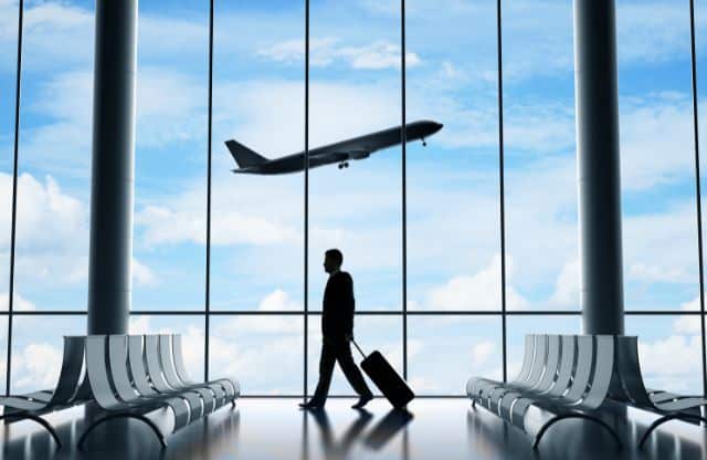 silouhette of traveller at airport with plane taking off as travel trends continue growing | HiRUM